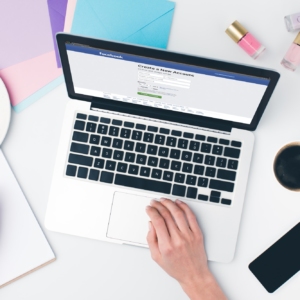top view of woman using laptop and writing in notebook with facebook website