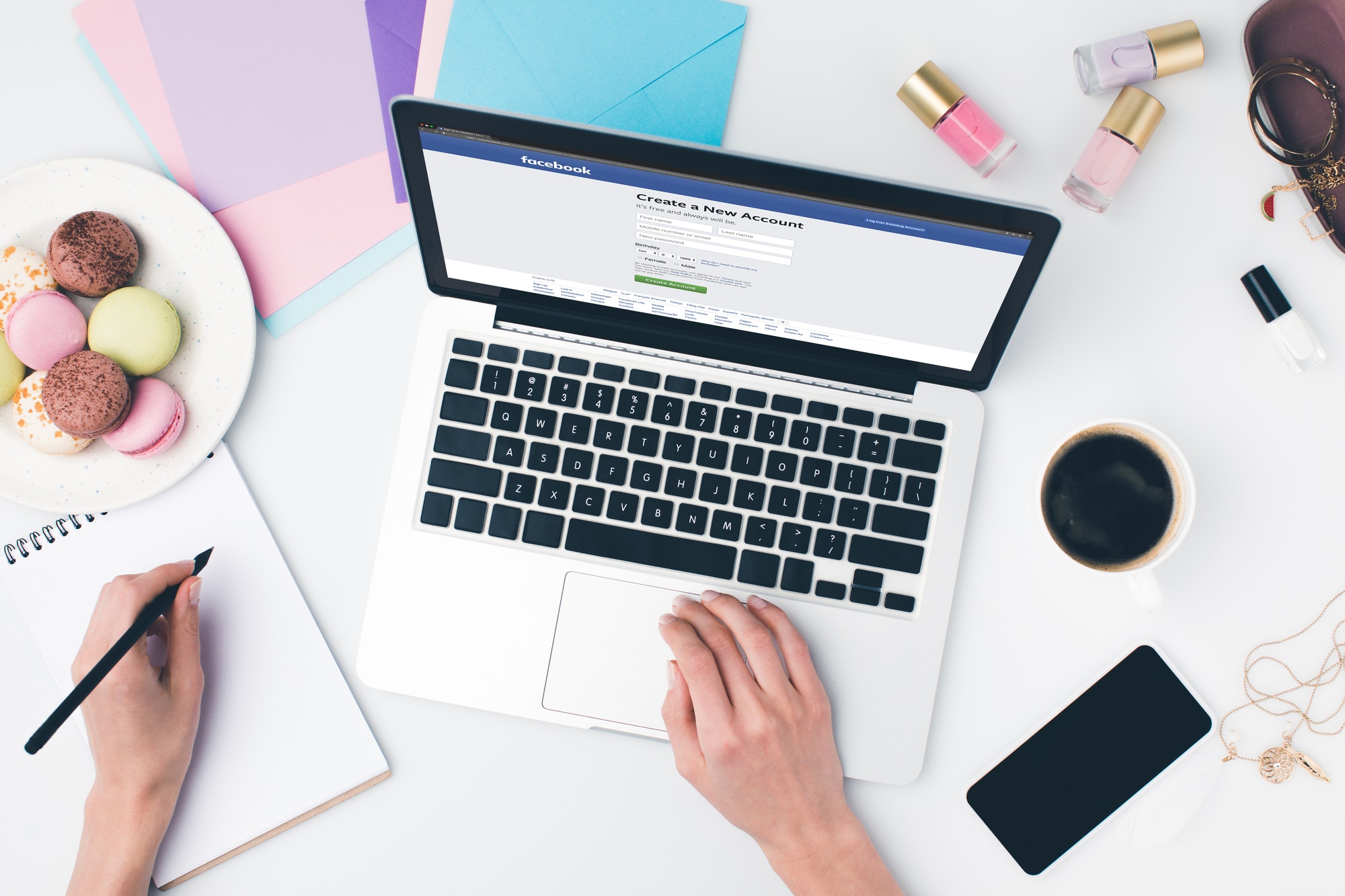 top view of woman using laptop and writing in notebook with facebook website