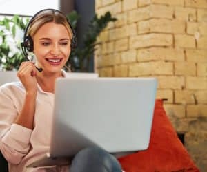 Charming business lady in headphones talking with business partner on laptop
