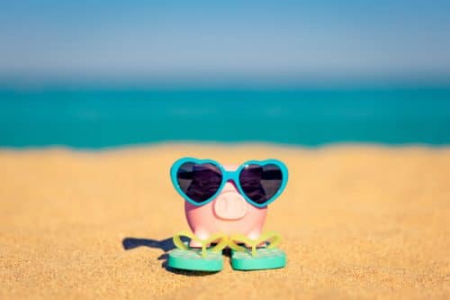 Piggybank on the beach against sea and sky background. Savings for summer travel and vacation concept